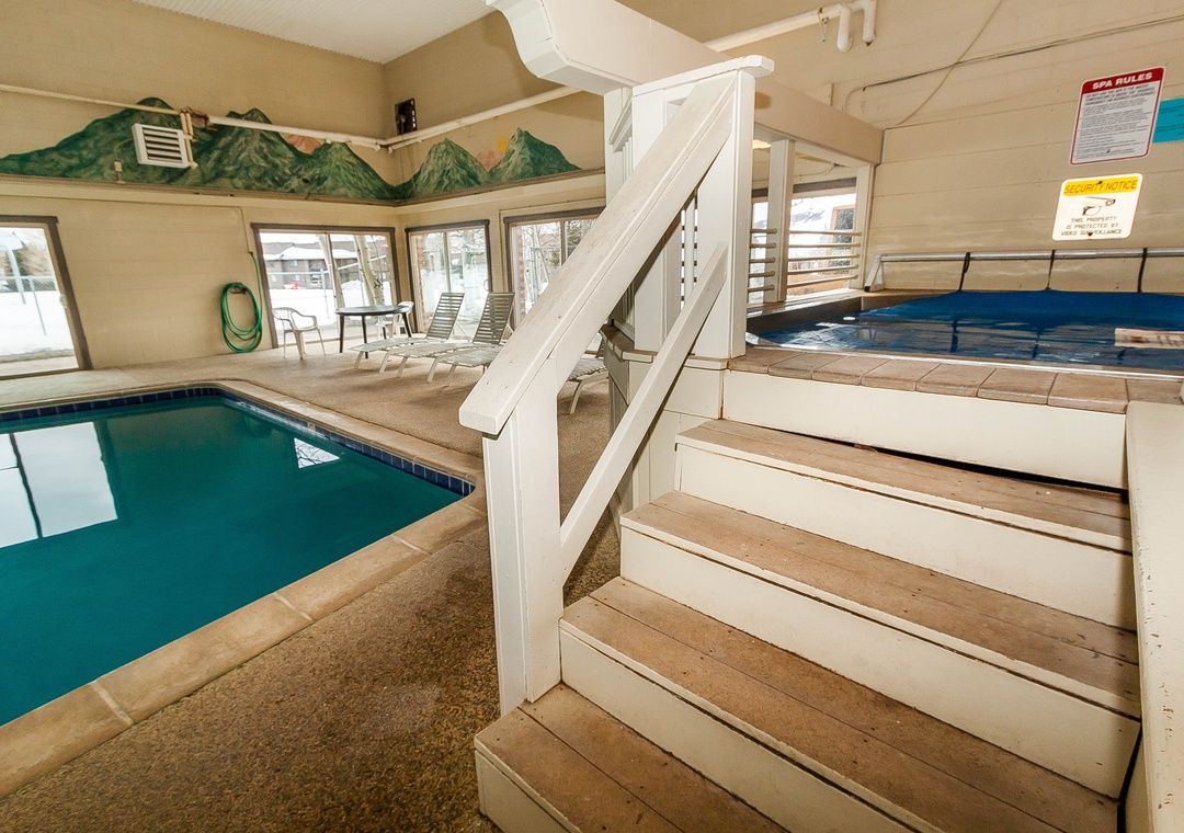 Una piscina interior con una escalera de madera que lleva a un vestuario.