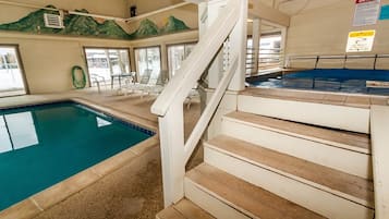 Una piscina interior con una escalera de madera que lleva a un vestuario.