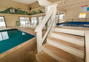 An indoor swimming pool with a wooden staircase leading to a changing room.