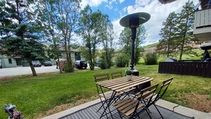 A patio with a table and chairs, surrounded by a grassy area and trees. - Cozy first floor condo with yard, near Keystone Resorts (Dillon)