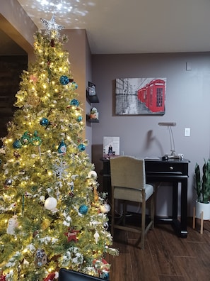 Une pièce bien éclairée, avec un sapin de Noël décoré, un bureau avec un ordinateur et une chaise.