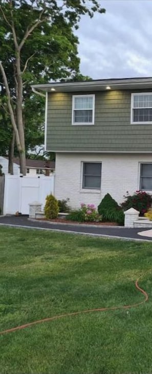 A two-story house with a well-maintained lawn and a garden with various plants and flowers.