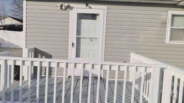 Une maison à l’extérieur blanc, avec une porte d’entrée et une petite fenêtre.