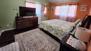 Une chambre à coucher avec un lit, une commode, un téléviseur et un luminaire au plafond.