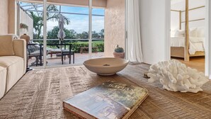 A spacious living area with a large window, a sofa, a coffee table, and a book. - The House on Castlelawn (Naples)
