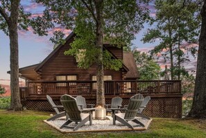 Relax in the cabin's outdoor space, surrounded by mature trees and a central fire pit.