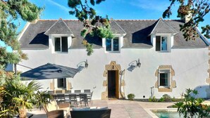A two-story house with a patio, outdoor seating, and a swimming pool.