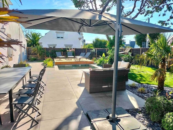 An outdoor patio with a pool, lounge chairs, and a dining area.