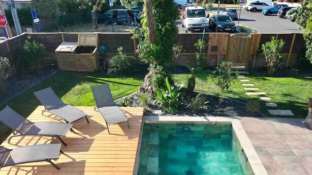 A backyard with a wooden deck, a swimming pool, and a fenced area.
