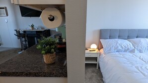 Una habitación compacta con kitchenette, una cama y un pequeño comedor.