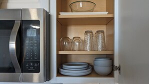 Una cocina con microondas, un mueble con vajilla y un tazón sobre la encimera.