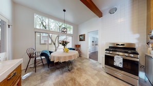 A kitchen with a modern stove, a dining area with a table and chairs, and large windows allowing natural light. - Beautiful Downtown Home (Nevada City)