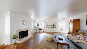 A spacious living room with a fireplace, wooden flooring, a sofa, and a large window. - Beautiful Downtown Home (Nevada City)