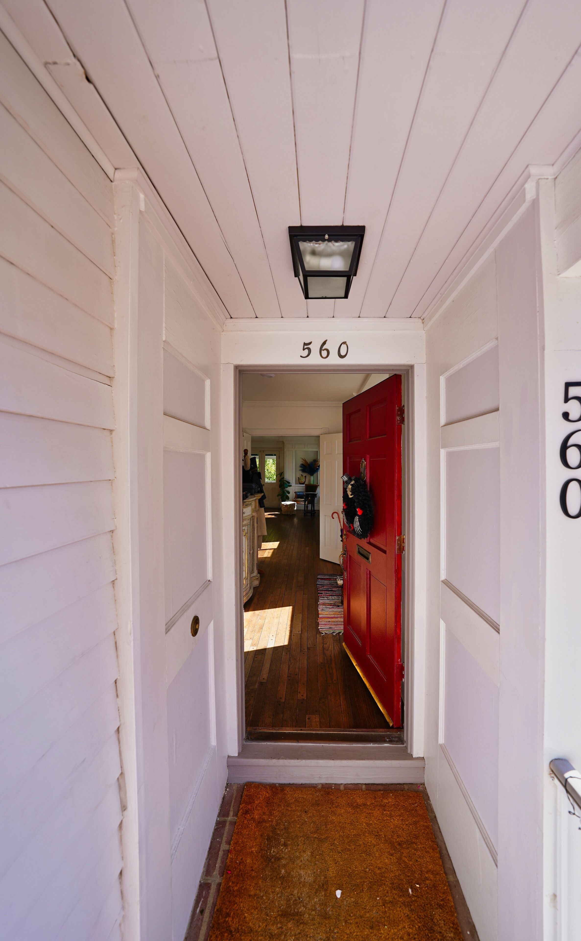 A hallway with white doors, a red door, and a number '560' above the entrance.