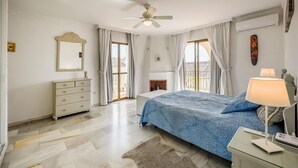 A bedroom with a bed, a dresser, a mirror, a ceiling fan, and a window with curtains. - Beautiful apartment in Mijas with swimming pool (Mijas)