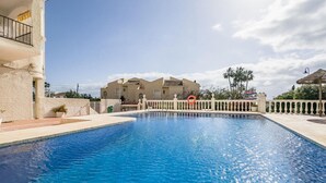 A swimming pool with a white fence, a lifebuoy, and a building in the background. - Beautiful apartment in Mijas with swimming pool (Mijas)