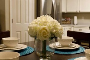 A dining table with a vase of white flowers, white plates, and blue placemats. - Retreat 5 bed, 4 room 3.8 mi. from Redding Airport (Anderson)