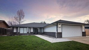 A modern single-story house with a garage, a well-maintained lawn, and a clear sky.