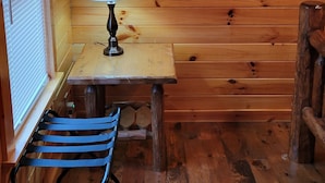 A wooden cabin interior with a table, lamp, and a bench. - The Getaway #15 (Ashtabula)