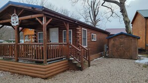 A wooden cabin with a porch, a covered deck, and a small shed. - The Getaway #15 (Ashtabula)