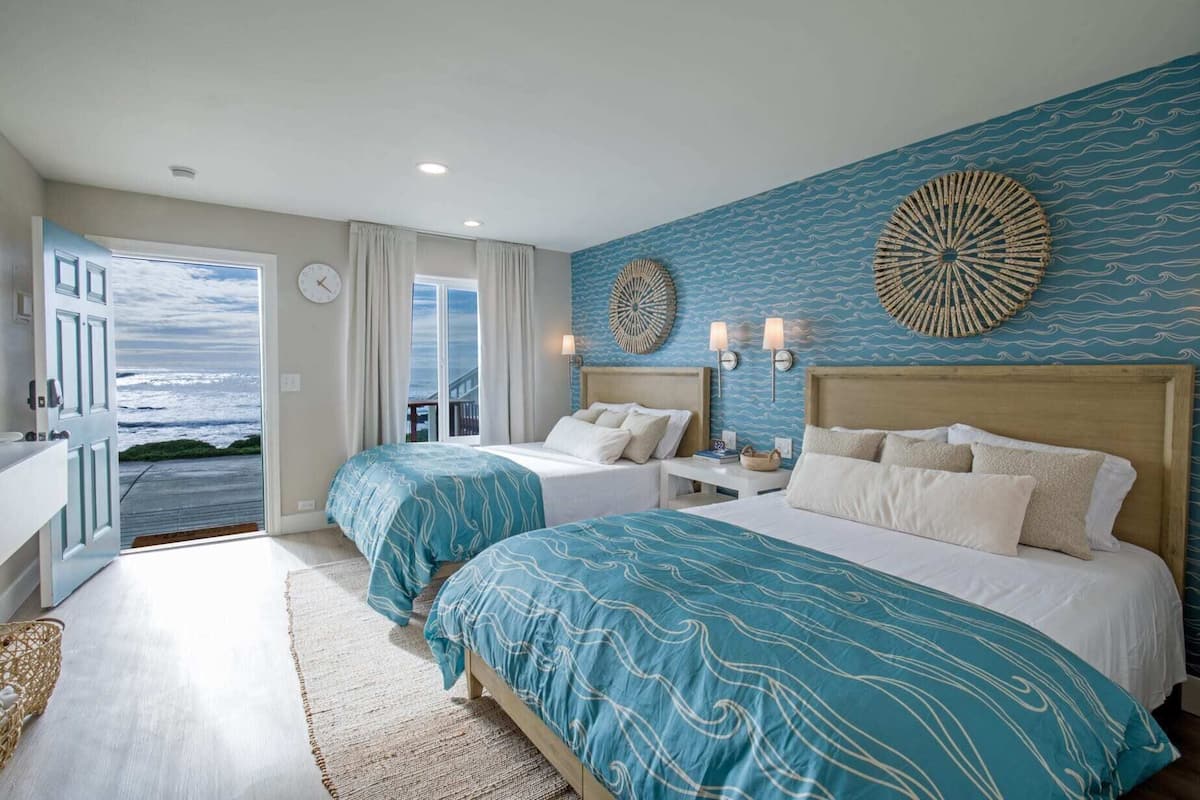 A bedroom with two beds, a view of the ocean, and a clock on the wall.