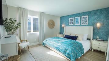 A bedroom with a bed, bedside tables, a TV, a plant, and a window with curtains.