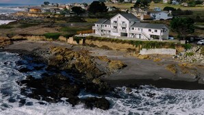 A coastal house with a balcony, situated near the beach with waves crashing in the foreground. - Black Sands Inn (Shelter Cove)