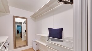 Een kleine kamer met een stapelbed, een spiegel, een witte prullenbak en een klein tafeltje met een mandje.