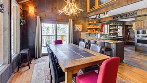 Un comedor amplio con una gran mesa de madera y sillas rojas, un candelabro y una zona de cocina con un letrero que dice "I LOVE THIS PLACE".