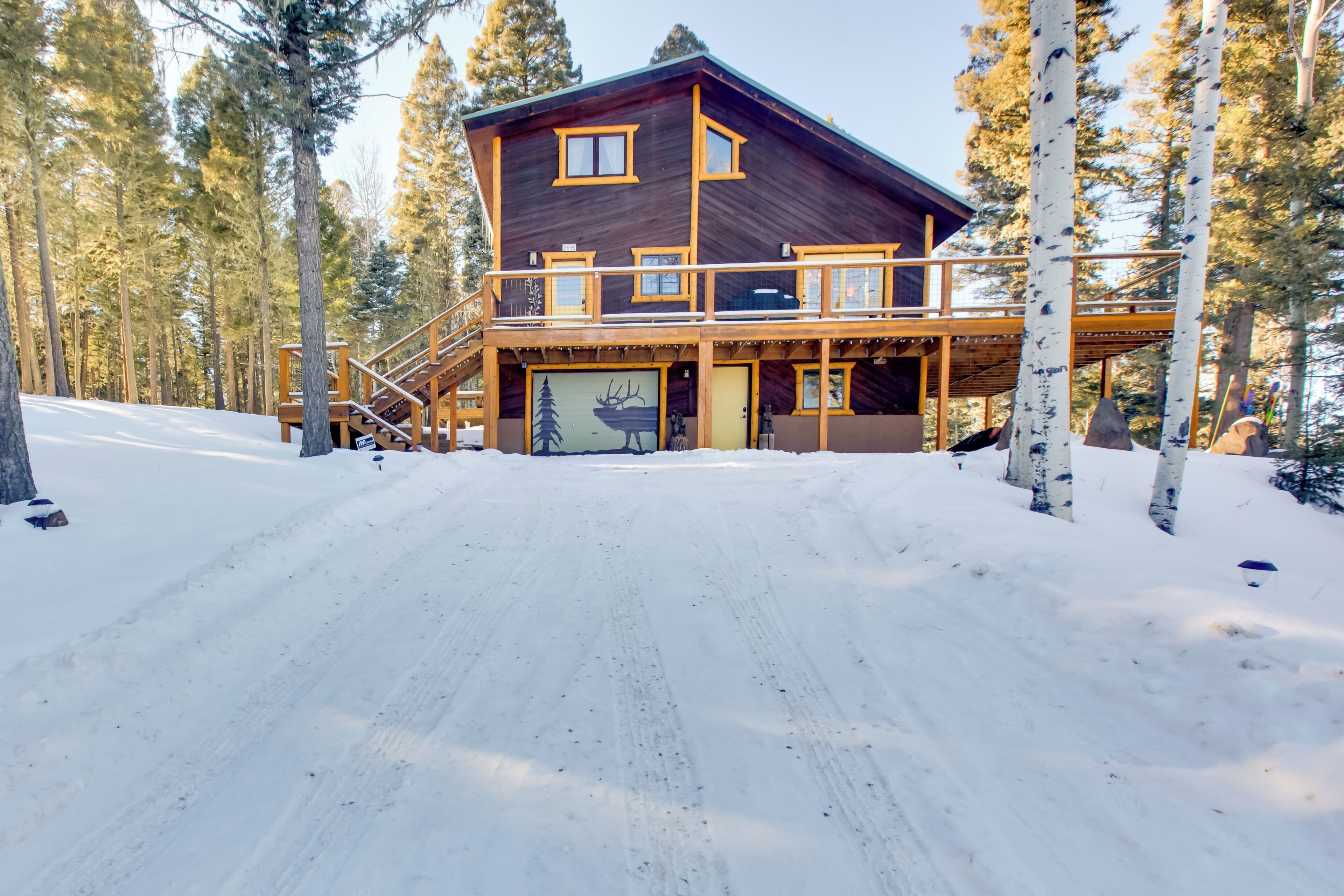 A wooden cabin with a balcony and a garage door with a deer mural.