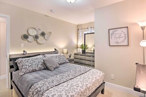 A bedroom with a bed, bedside tables, a dresser, a mirror, and wall decor. - Fort Lauderdale Apt Near Beaches & Shopping! (Fort Lauderdale)