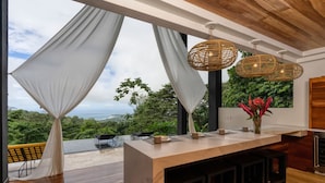 A modern kitchen with a large island, white curtains, and a view of the outdoors. - BEAUTY OF COSTA RICA STUNNING VIEW (Uvita)