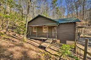 Eine rustikale Holzhütte mit Veranda, einem kleinen angebauten Schuppen und einer Holztreppe, die zum Eingang führt.