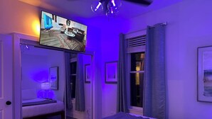 Une chambre à coucher avec un lit, une télévision et une porte donnant sur une salle de bain.