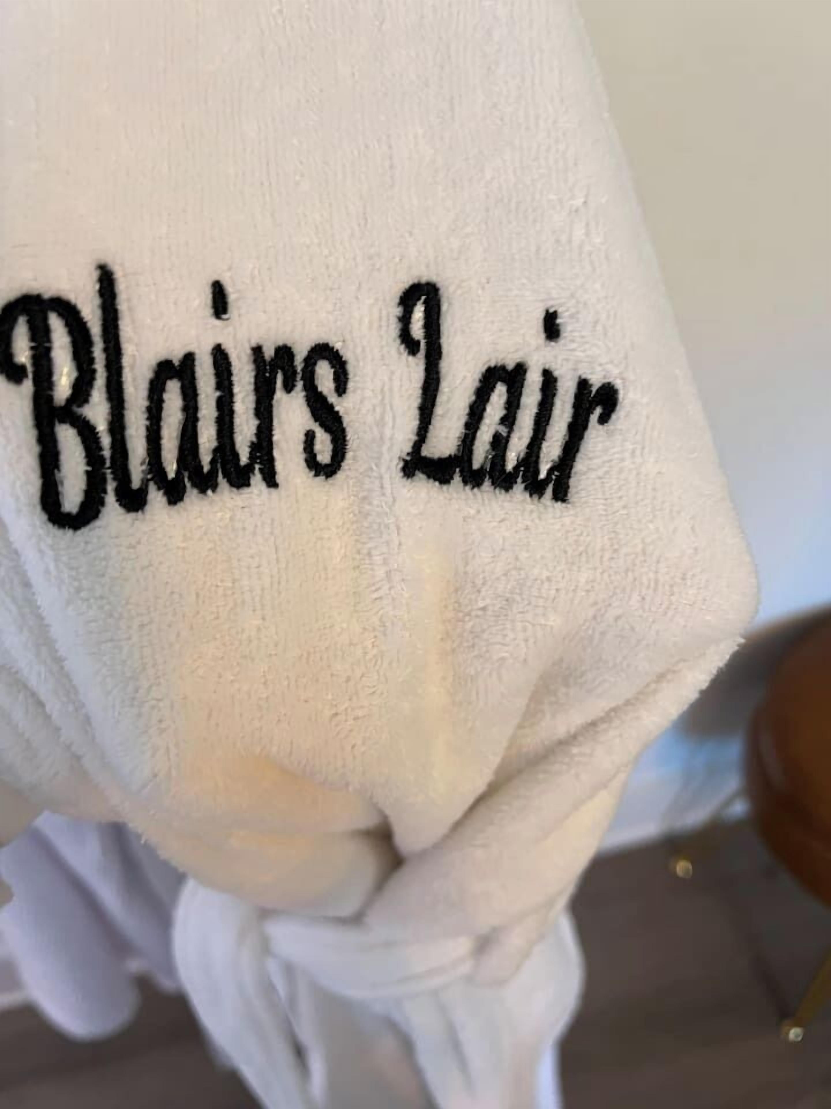 A towel with embroidered text reading "Blairs Lair".