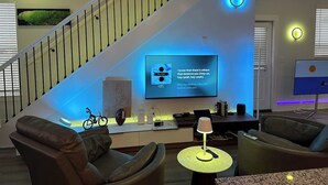 Un salon moderne avec un escalier, un téléviseur à écran plat et une table basse.
