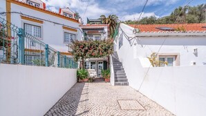 A narrow cobblestone alleyway between buildings with white walls and red-tiled roofs. - JOIVY Elegant Beach Studio (Portinho da Arrábida, Azeitão)