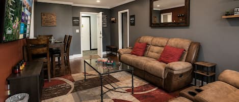 A living room with a sofa, a coffee table, and a TV mounted on the wall.