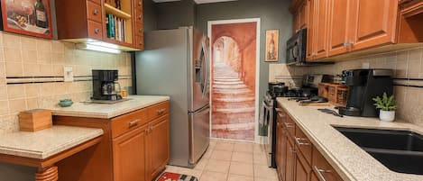 A kitchen with wooden cabinets, a refrigerator, a microwave, and a coffee maker.