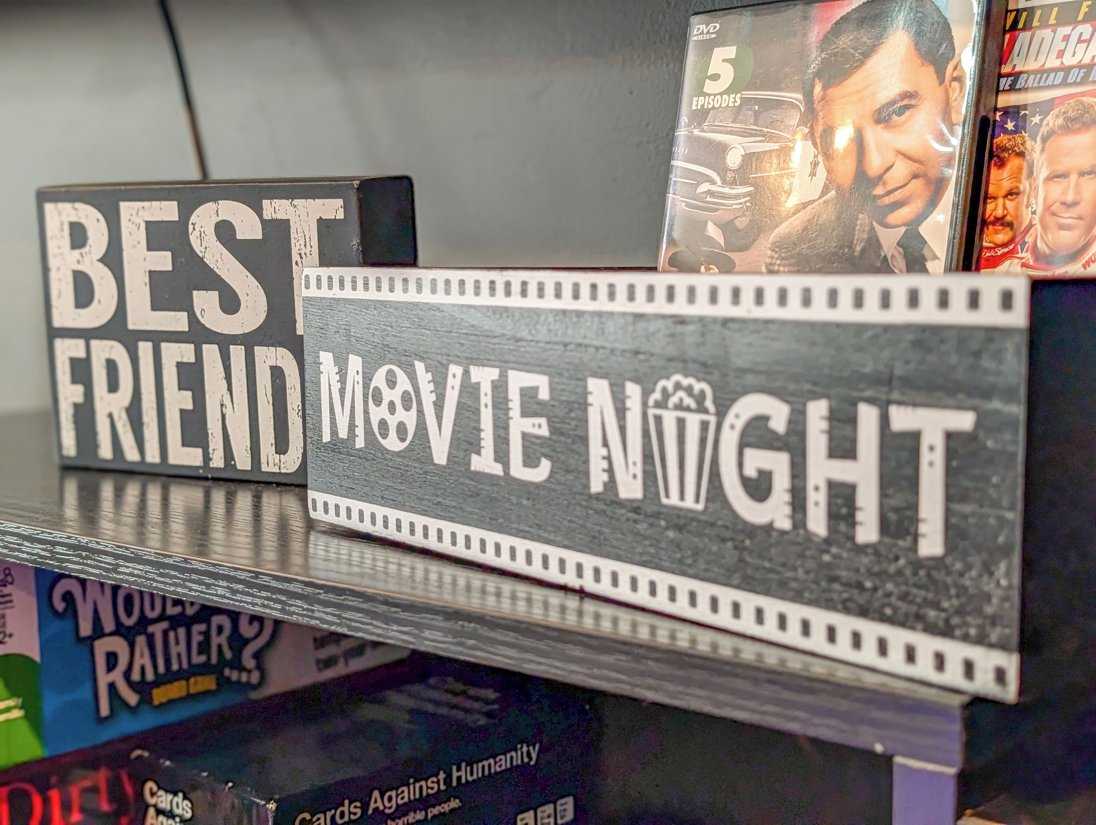Een dvd-rek met filmtitels en een bordje waarop staat 'BEST FRIEND MOVIE NIGHT'.