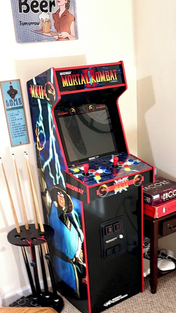 A video game arcade machine with Mortal Kombat branding, a joystick, and buttons.