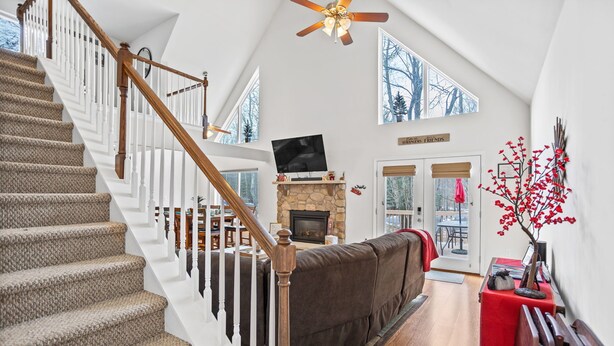 A spacious living area with a stone fireplace, a large TV mounted above it, and a cozy seating area with a brown sofa. - Charming Towamensing Trails Chalet - Sleeps 9, Fireplace, BBQ Deck & Large Yard (Albrightsville)
