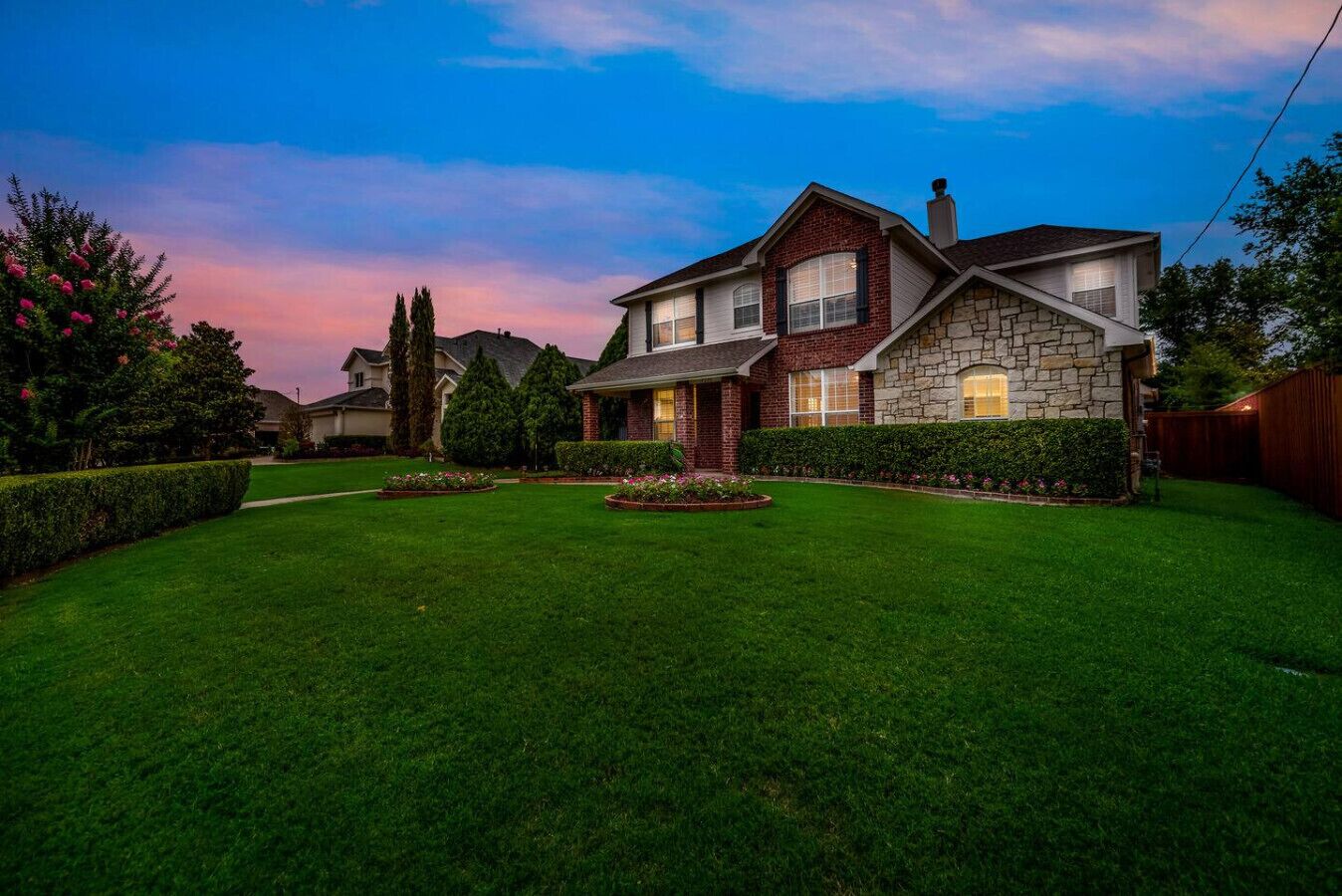 A two-story house with a stone facade and a well-maintained lawn.