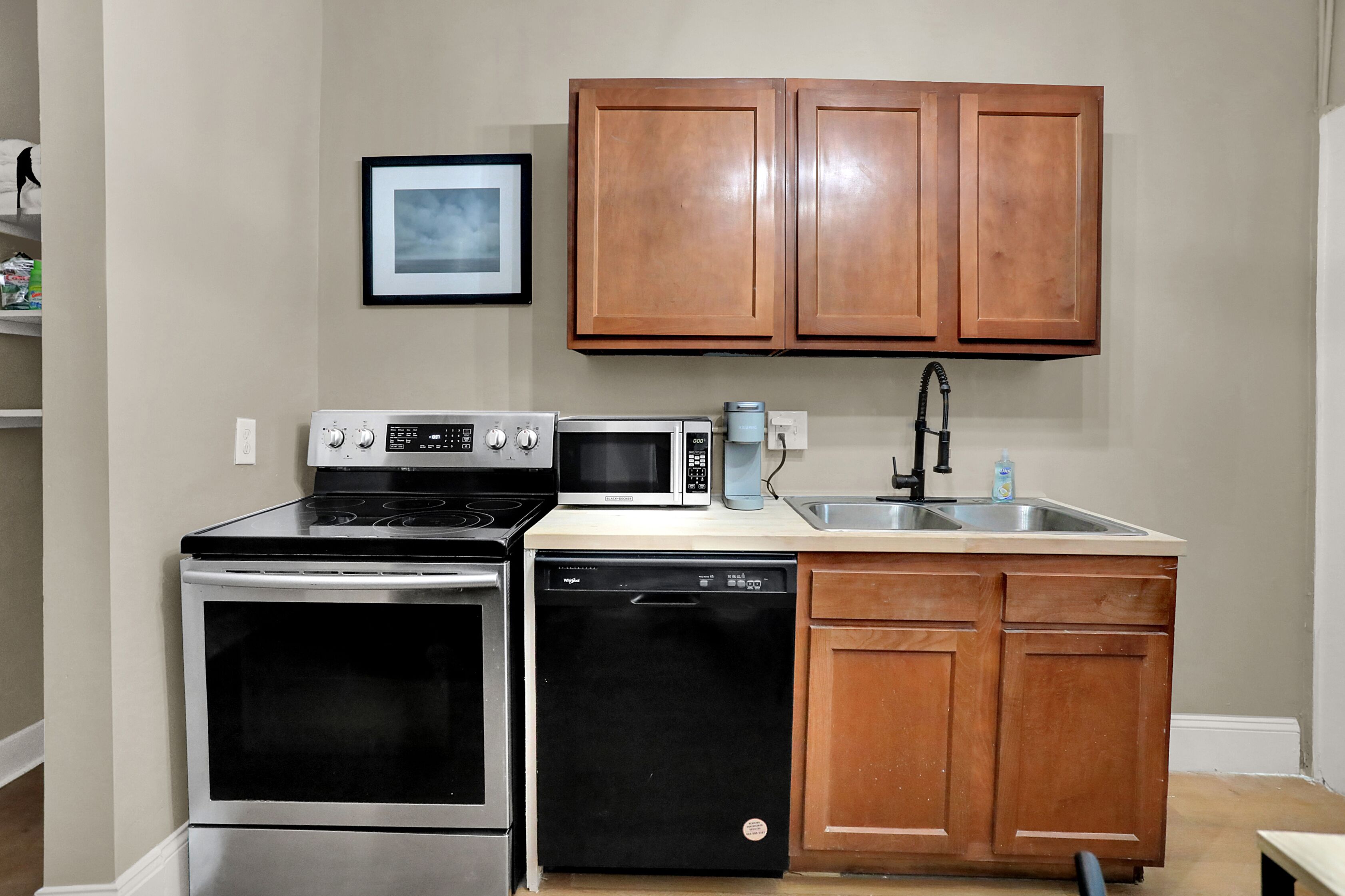 A kitchen with wooden cabinets, a microwave, a stove, and a dishwasher.