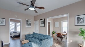 A spacious living room with a sectional sofa, a dining area with a table and chairs, and a ceiling fan. - The village (Indianapolis)