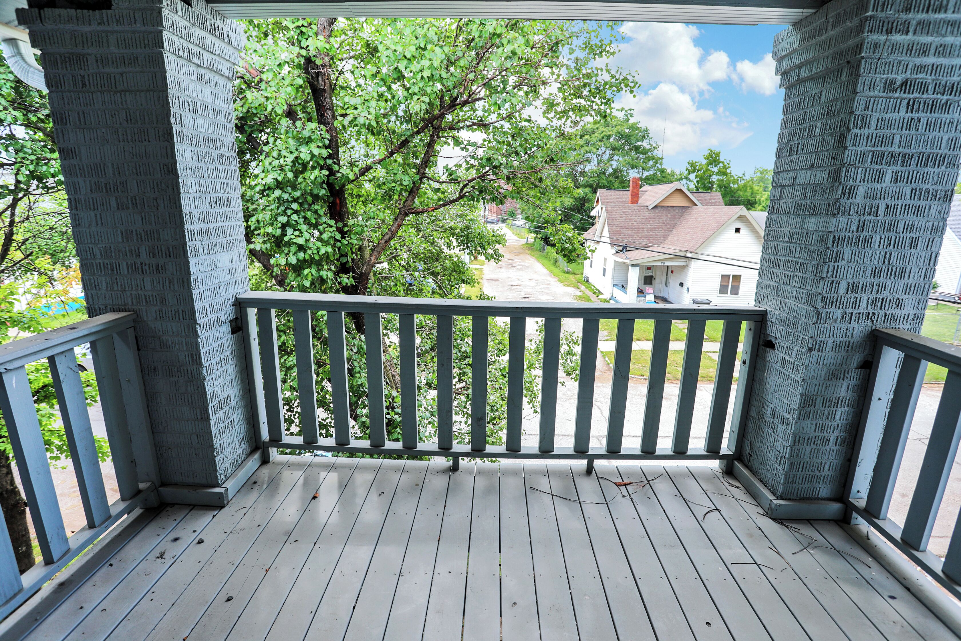 A covered porch with a view of a residential street.