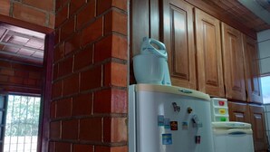 Una cocina con pared de ladrillo, armarios de madera y un refrigerador blanco con imanes.