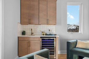 Cocina moderna con armarios de madera, un refrigerador para vinos empotrado y vistas al exterior a través de un ventanal.