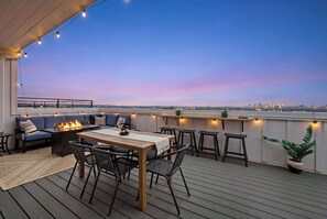 Una terraza en la azotea con zona de comedor, asientos y vistas del horizonte urbano.