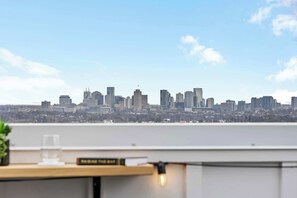 Un horizonte urbano con edificios modernos, cielo despejado y vista desde un balcón.